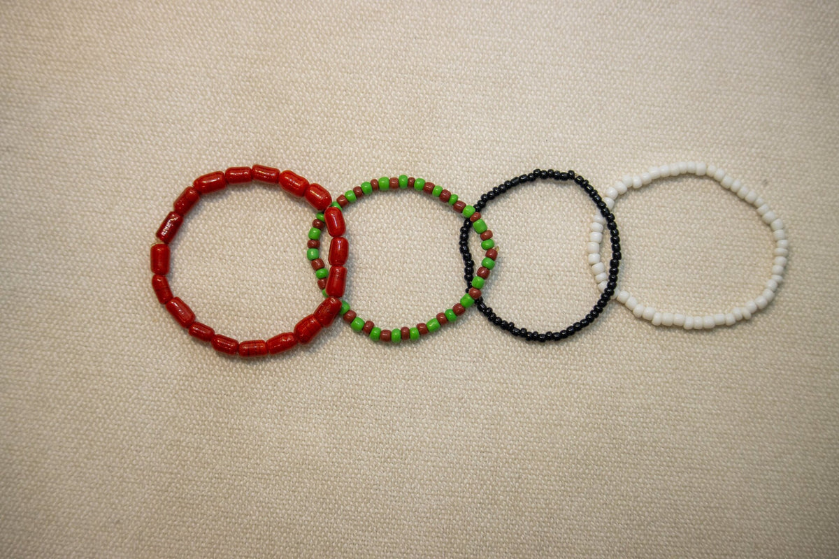 Three-strand coral, white, and green bead bracelet on wrist