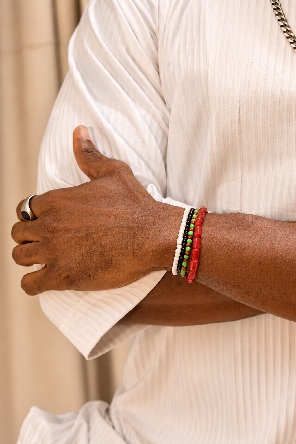Three-strand coral, white, and green bead bracelet on wrist